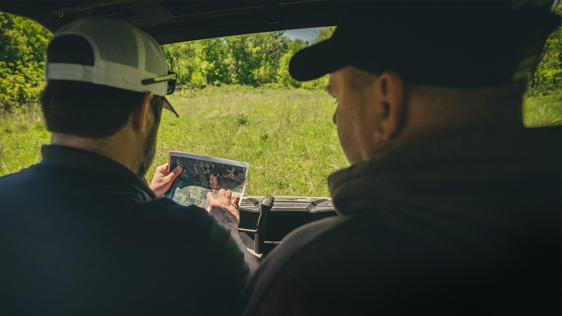 KILOTERRA land specialists reviewing a property map in a UTV